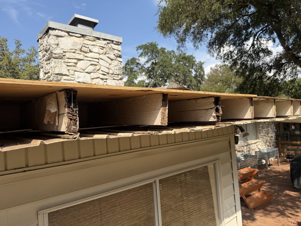 Rotted rafter tails and fascia exposed during a San Antonio roof repair, new pressure-treated ledger installed